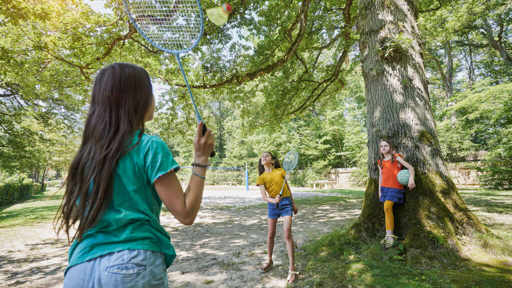 3 Kinder spielen Federball im Freizeitgelände
