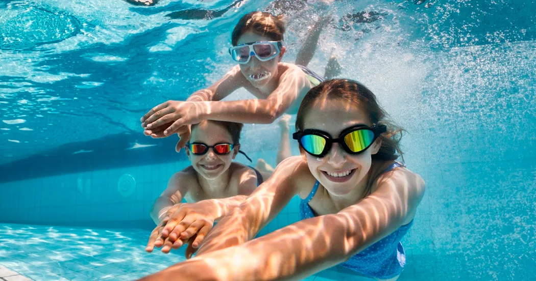 3 Kinder tauchen mit Schwimmbrillen im Schwimmbecken Unterwasser