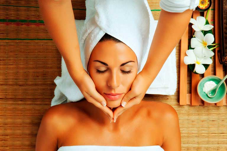 Frau liegt auf dem Rücken und bekommt eine Gesichtsmassage