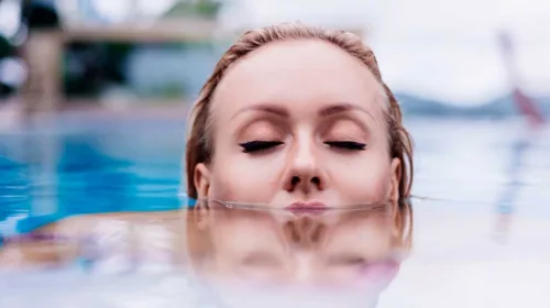 Fau schwimmend im Wasser mit Kopf teilweise im Wasser und geschlossenen Augen